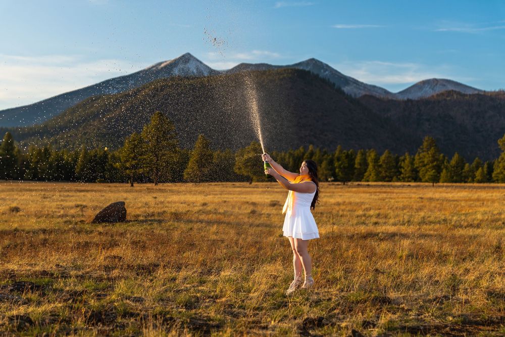 Graduate celebrates in scenic mountain landscape during sunset photo session.