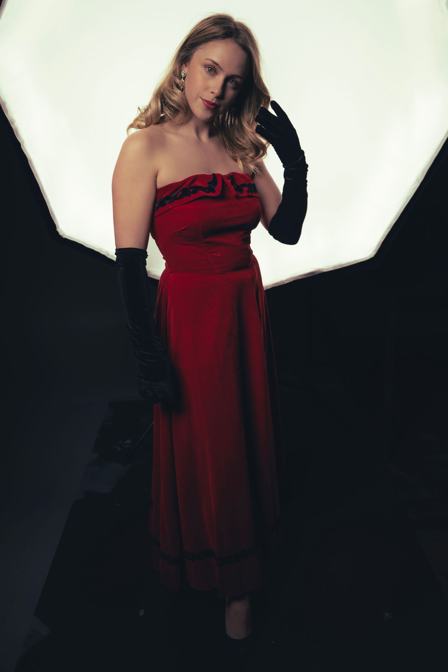 A woman poses in a red strapless dress against a white backdrop in a series of fashion photography shots.