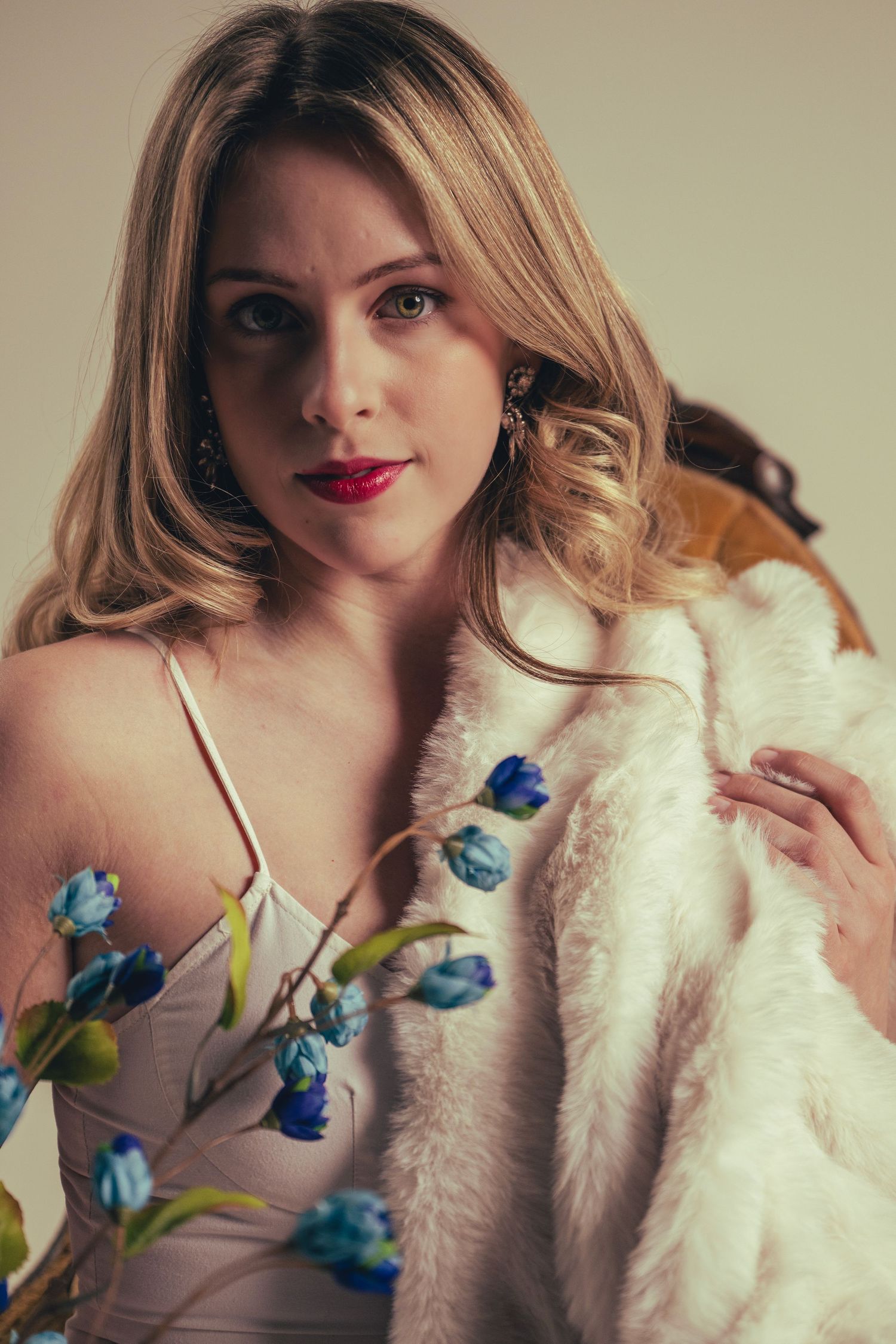 Glamour portrait series featuring a white fur coat and blue flowers against a neutral background.