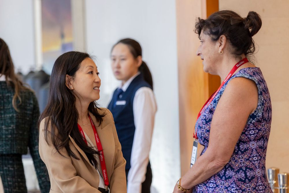 People engaged in animated conversation during a professional networking event in an office setting.