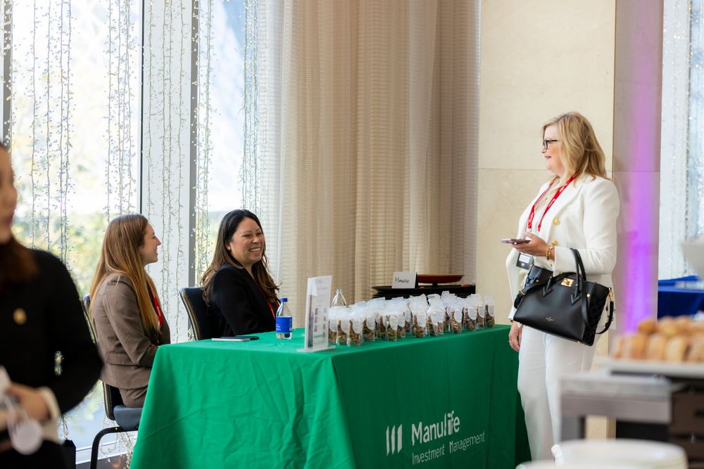 Business professionals seated at tables with green tablecloths during a corporate conference or meeting event.