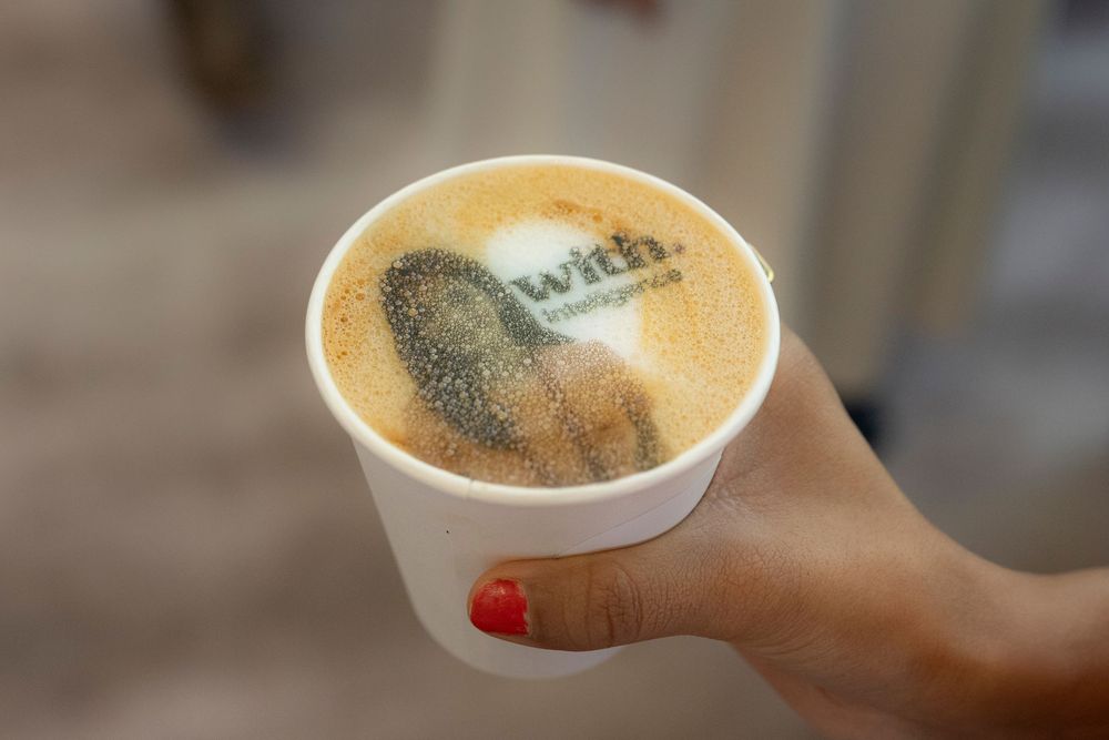 A series of hands holding various coffee drinks with intricate latte art patterns in ceramic cups.