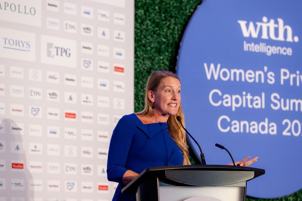 Professional speaker presenting at Women's Private Capital Summit Canada conference with projection screen in background.