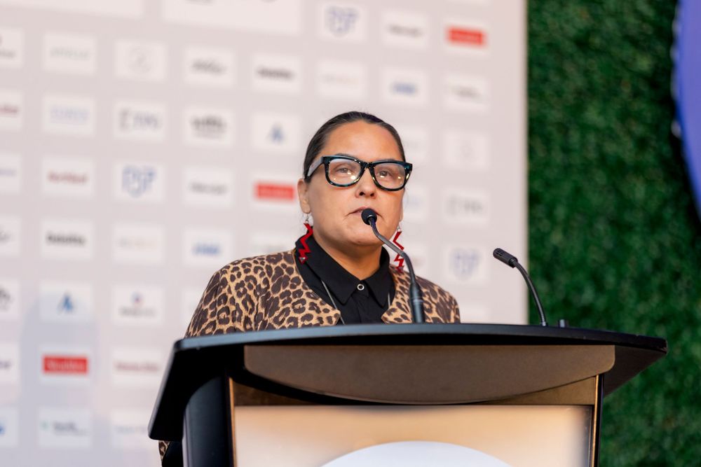 Speakers presenting at a conference podium with a branded backdrop and microphone.