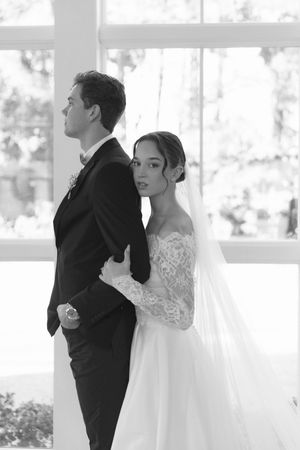 Bride and groom share an intimate moment in black and white during their first look at an elegant wedding ceremony.