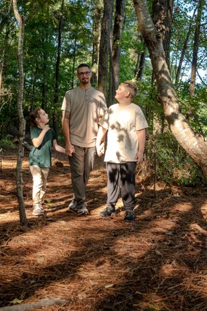 A sequence of four photos showing people walking on a wooded trail with dappled sunlight filtering through the trees.