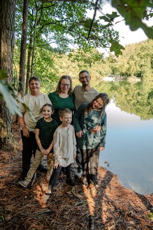 Group enjoying a sunny afternoon by a tranquil lake surrounded by pine trees and natural scenery.