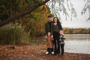 A collection of outdoor fall family portraits taken near a lake with autumn foliage in the background.
