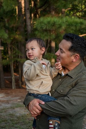 A touching outdoor moment between a parent and child playing together in a wooded setting at sunset.