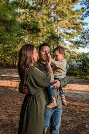 A family shares tender embraces and joyful moments together in a natural outdoor pine forest setting.