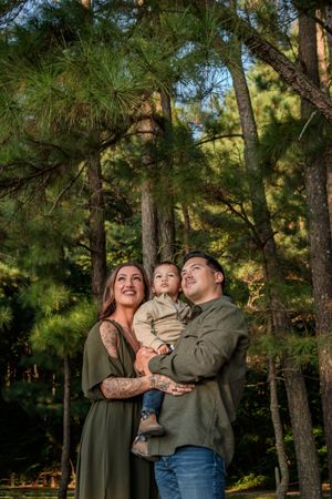 A family shares joyful moments together while standing among tall pine trees in an outdoor forest setting.