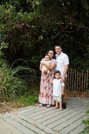 Family shares tender moments together on a wooden boardwalk surrounded by lush greenery.