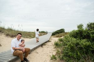 A series of candid beach engagement photos showing a couple enjoying tender moments on sandy dunes at sunset.