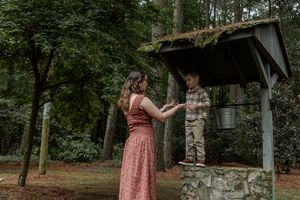 A bride in a pink dress poses in multiple outdoor settings with stone walls and natural greenery.