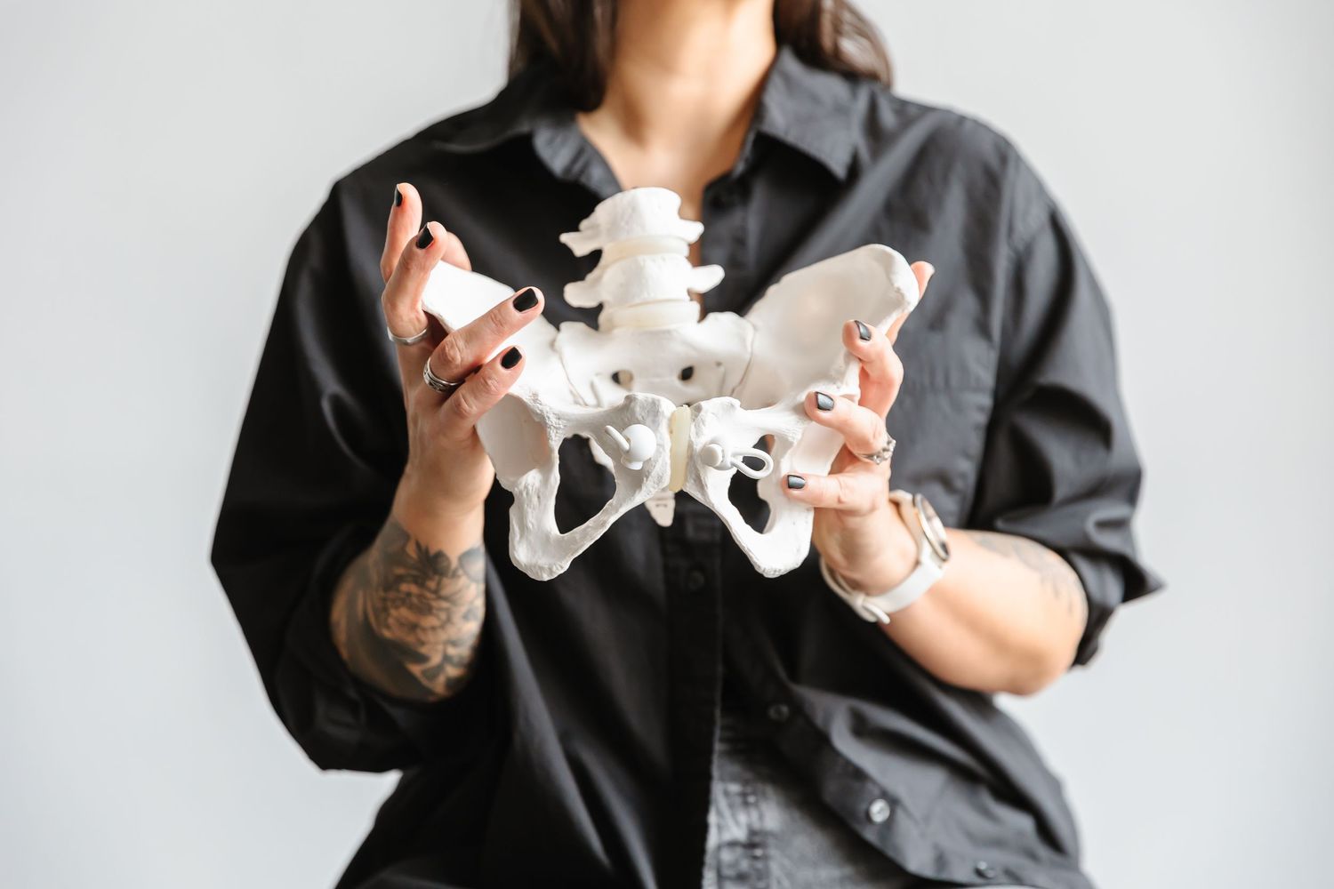A person wearing a dark shirt holds and examines pieces of a white plastic drone or quadcopter against a light background.