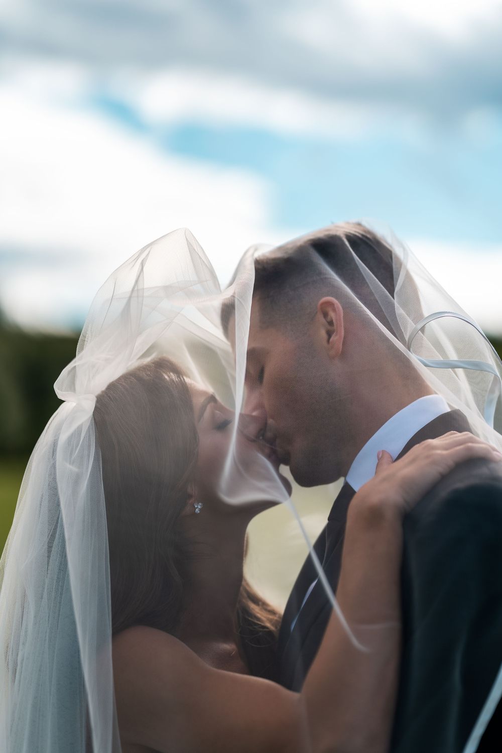 A romantic wedding sequence shows a couple sharing intimate kisses under a flowing white veil outdoors.