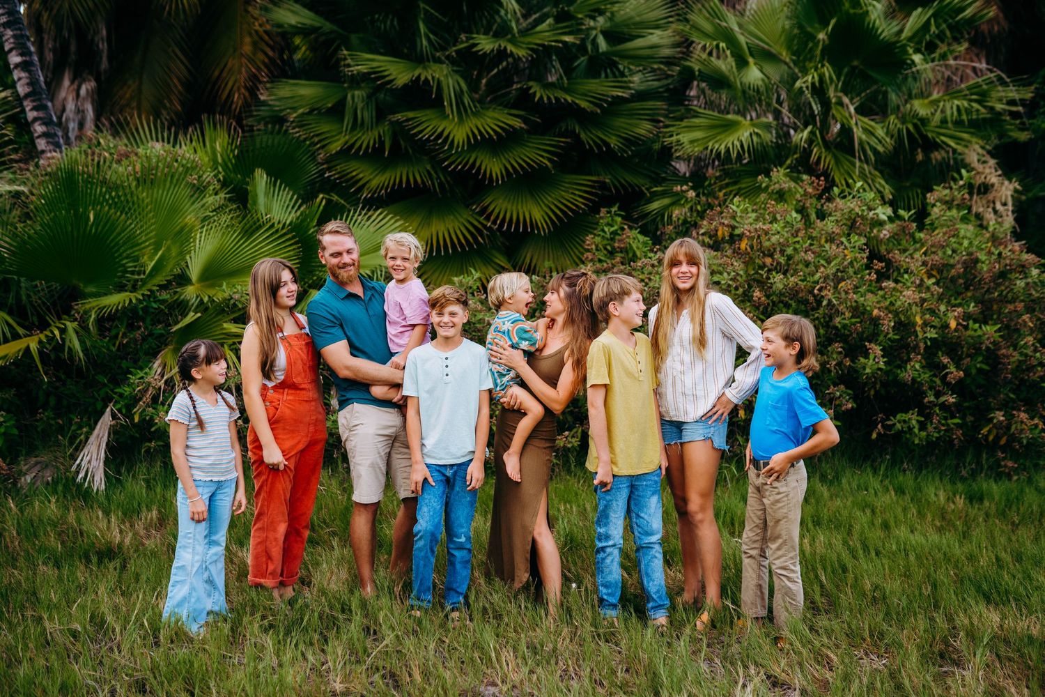 Large group in coordinated casual outfits gathered outdoors among lush greenery in kihei local family photography