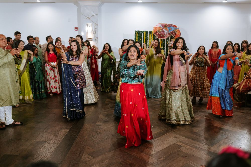 A group of people dancing in traditional ethnic clothing at a cultural celebration event in a large indoor space.