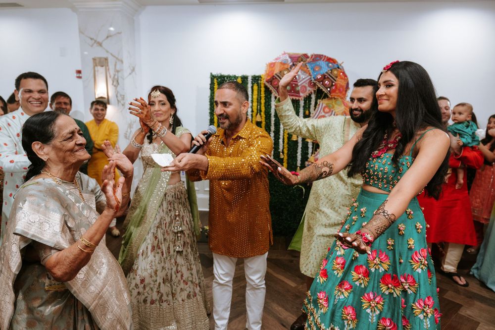 People dancing and celebrating at a festive indoor party wearing traditional Indian and fusion attire.