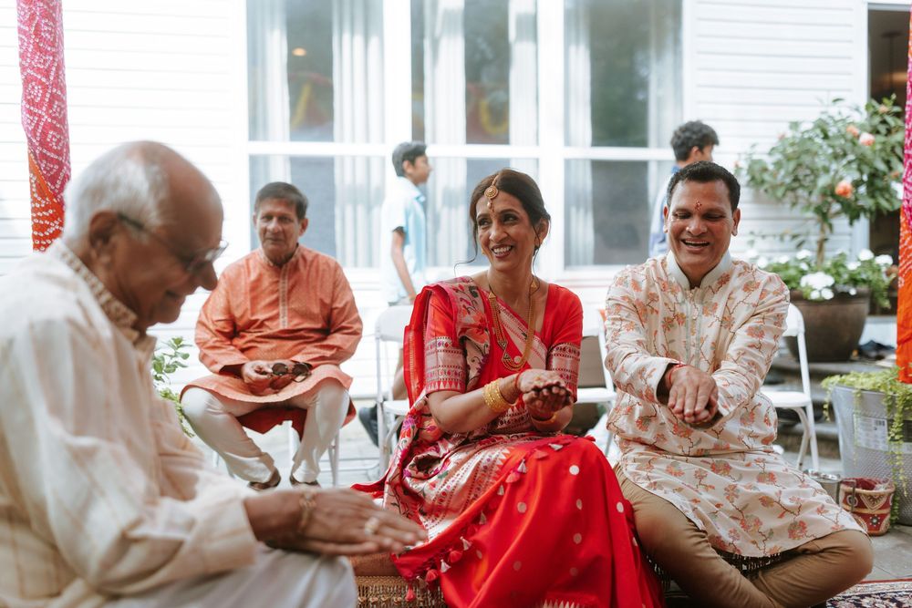 Elderly couple enjoying tea and conversation in a bright sunlit room with white and red decor.