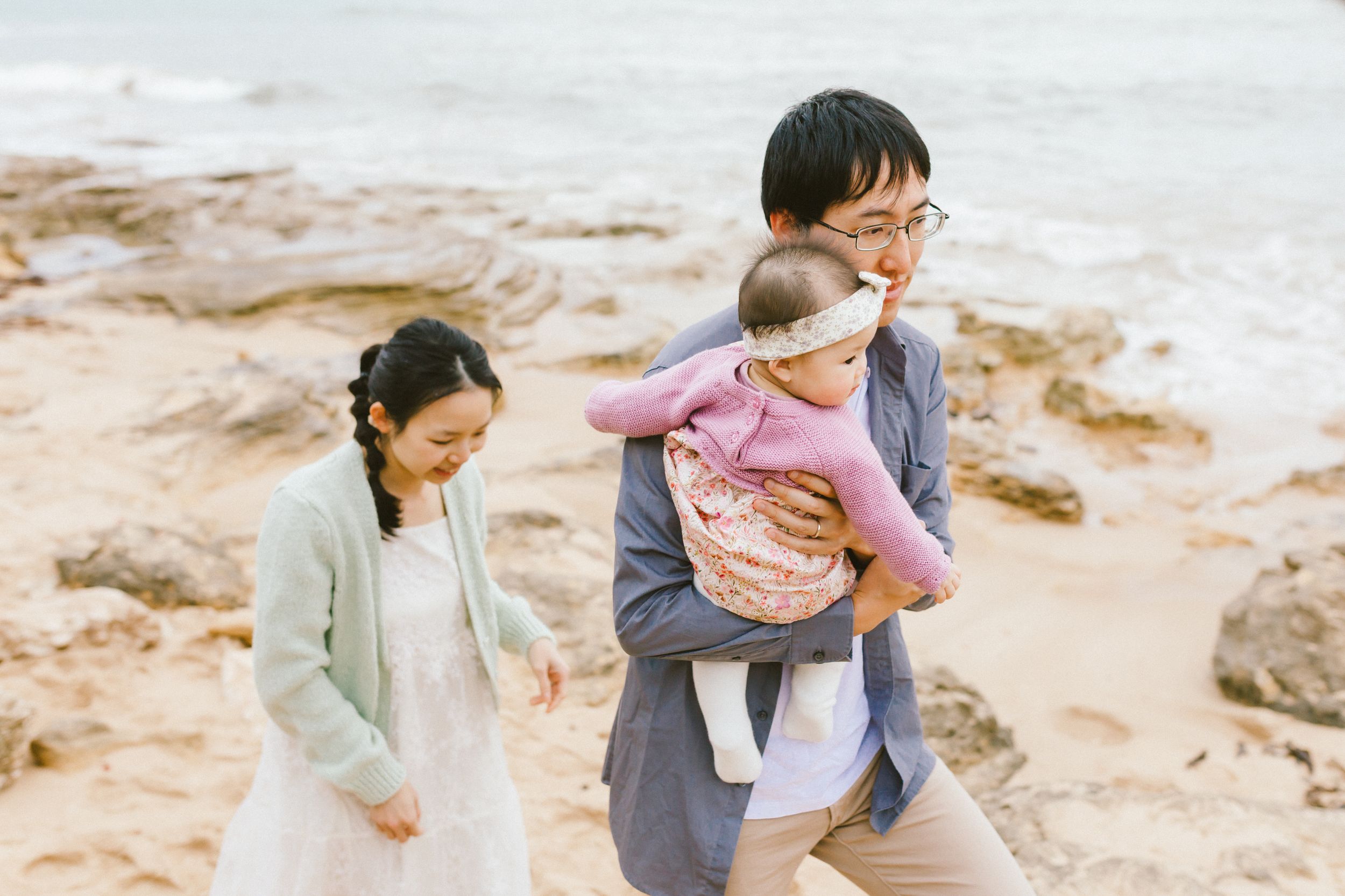 Family enjoying a day at the rocky beach, exploring tide pools and coastal areas together on a cloudy day.