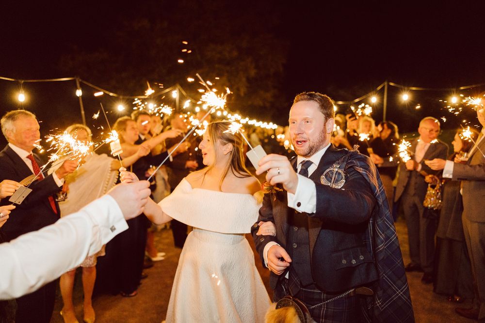 Couples dancing together at an evening wedding reception illuminated by warm glowing lights.