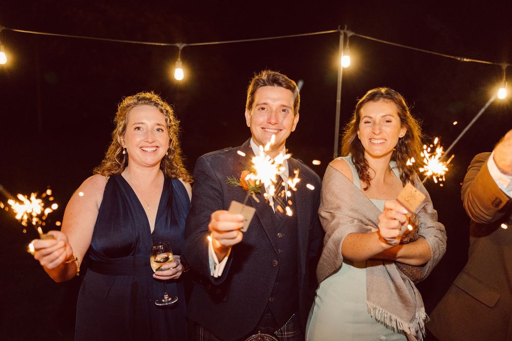 People holding sparklers at a nighttime celebration create a festive atmosphere with glowing lights.