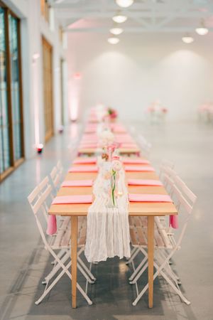 Elegant wedding reception table with pink napkins, white lace runner, and floral centerpieces.