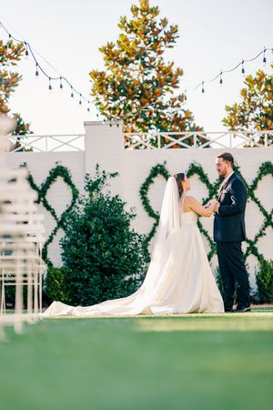Bride and groom sharing a romantic moment on a green lawn at outdoor wedding venue.