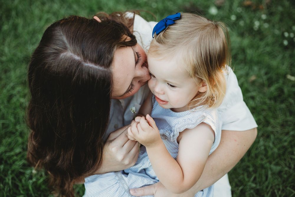 Tender family moment shared between parent and baby in lush green outdoor setting.