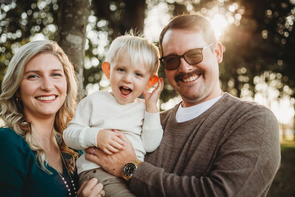 A happy family shares a joyful moment together outdoors during golden hour sunlight.