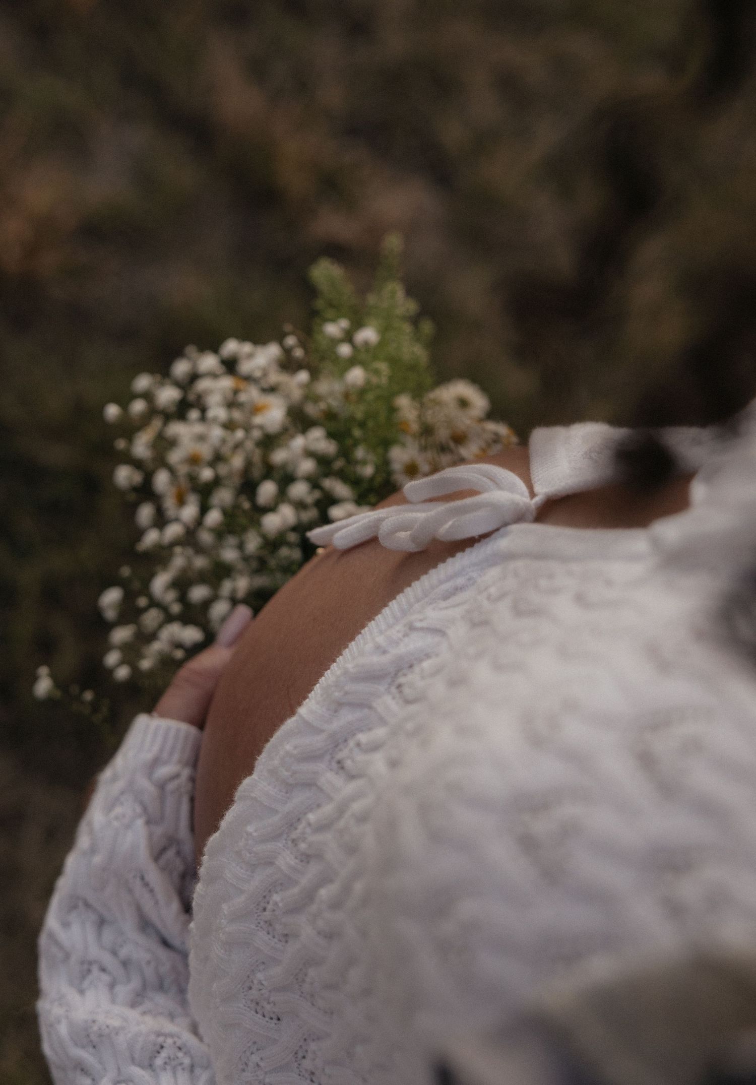 Close-up black and white photo showing pregnant belly in casual dress and jeans.