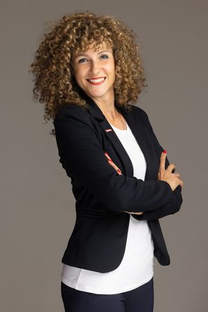 A series of professional portraits featuring someone in a black blazer and white top with curly hair in different poses.