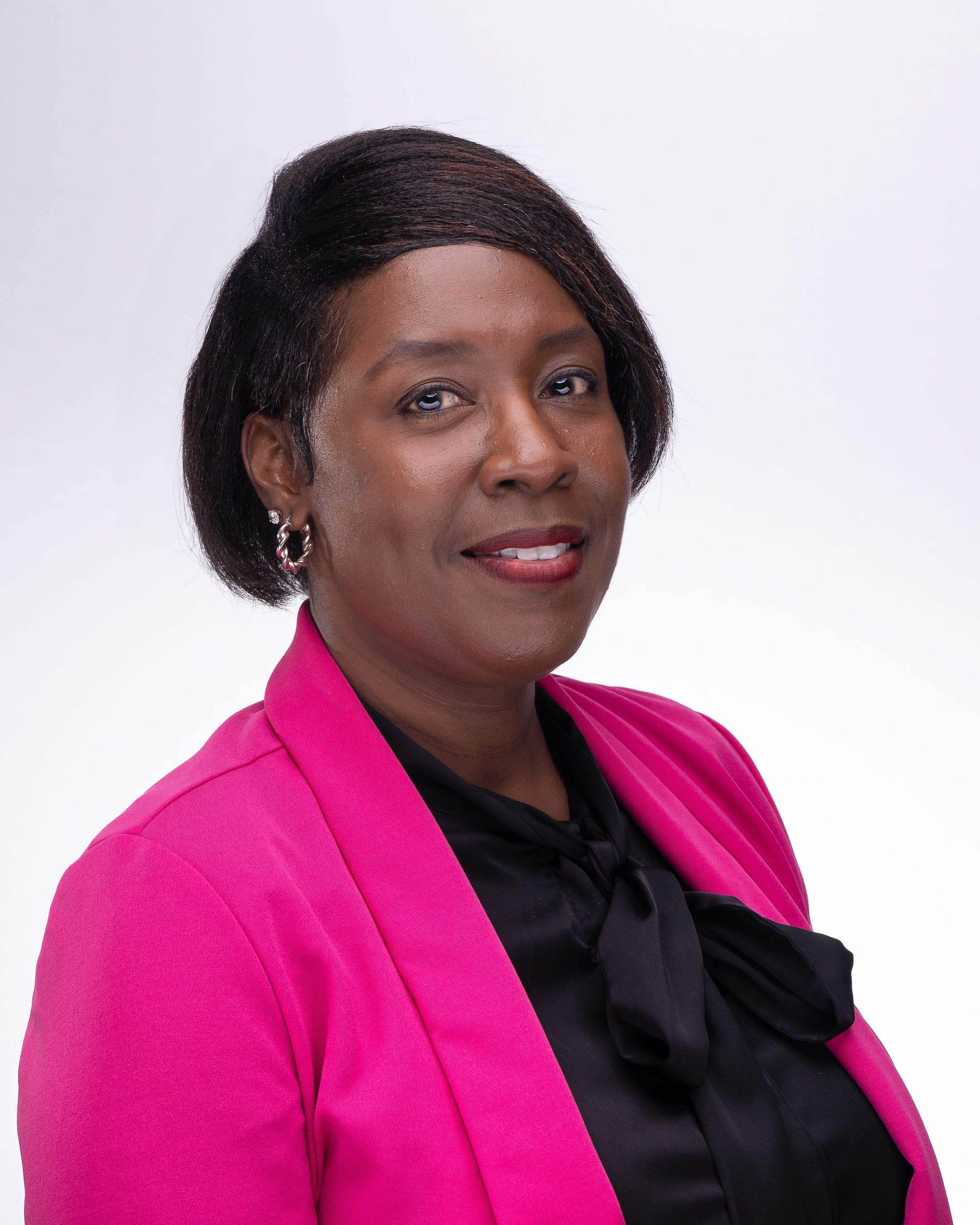 Professional headshot portrait in bright pink blazer and black blouse against light studio background.
