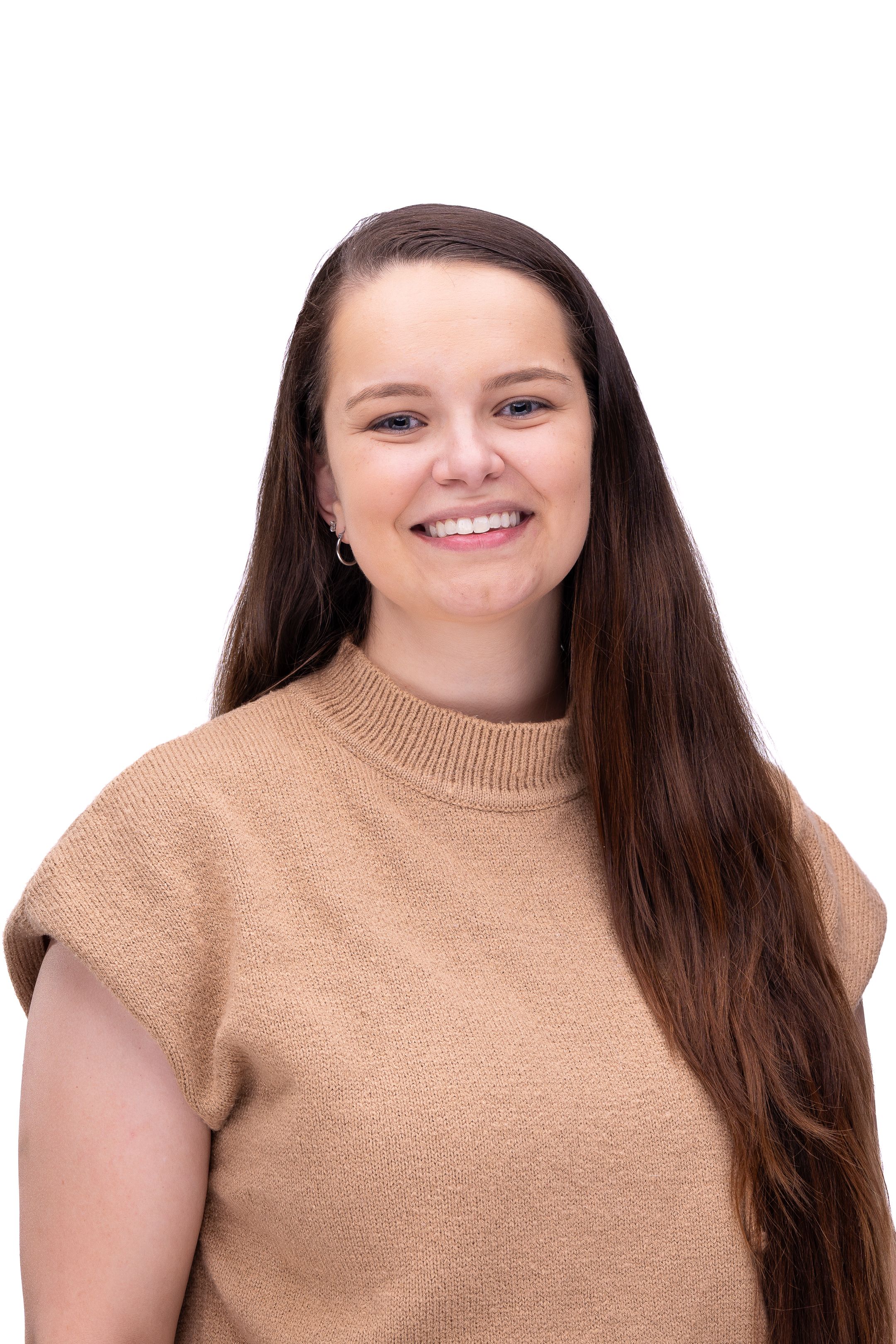 Portrait photo of someone with long brown hair wearing a beige sweater and smiling warmly against a white background.