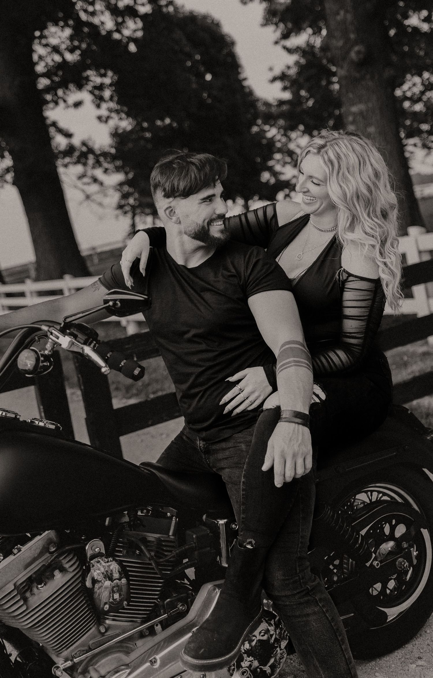 Intimate black and white portrait showing couple resting on vintage motorcycle.