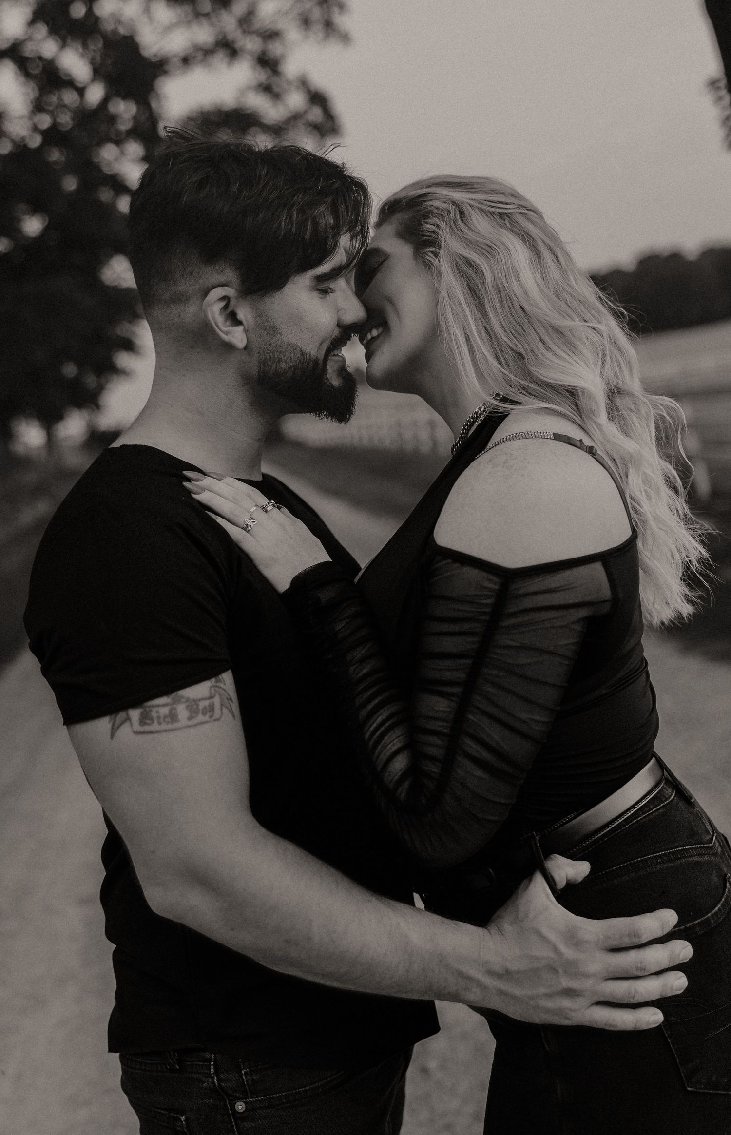 Intimate black and white portrait of couple embracing in casual attire.