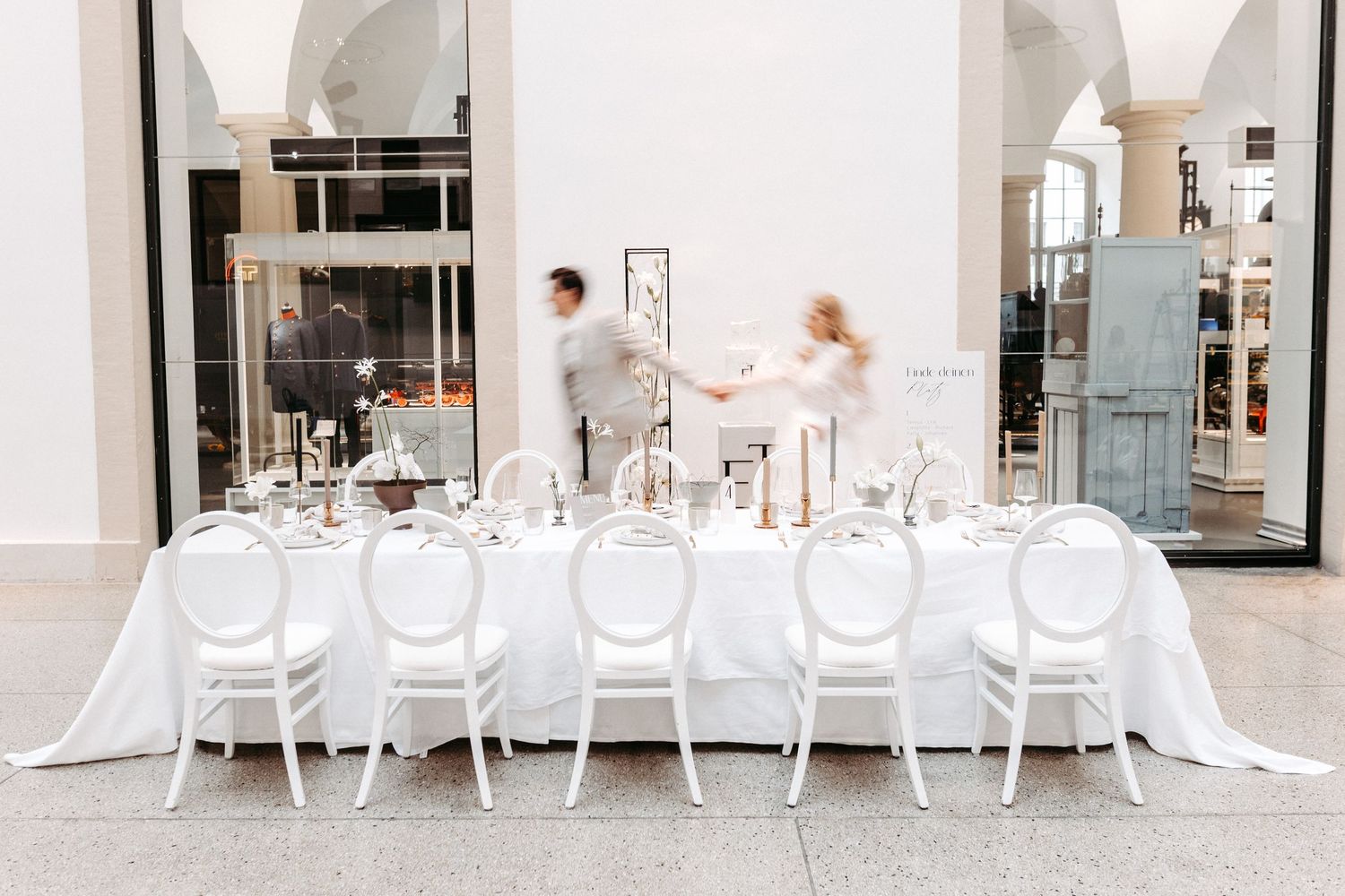 Elegant white dining table set with classic cross-back chairs at an upscale venue with flowing white linens.