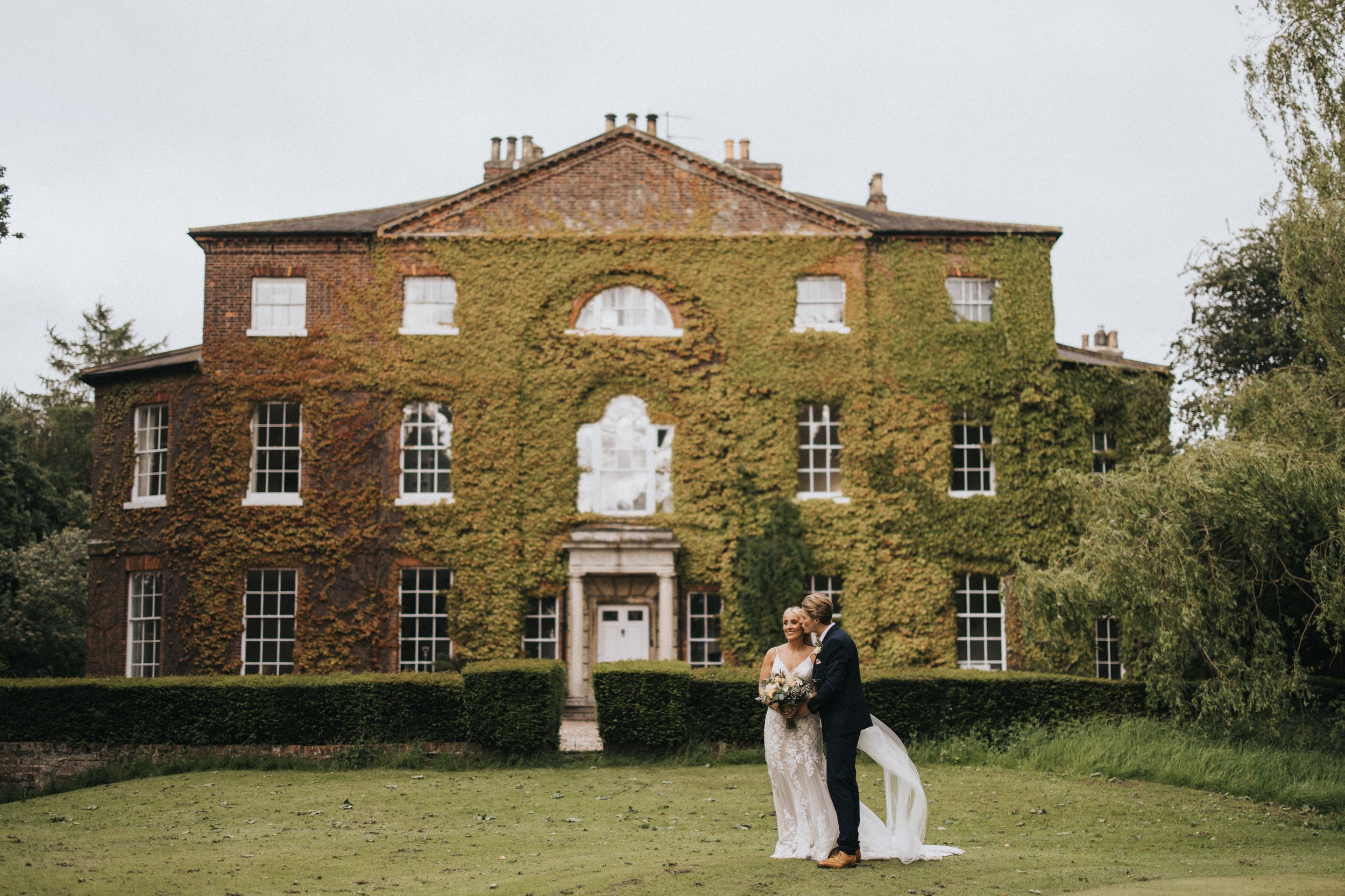 Elegant Georgian-style mansion with ivy-covered brick walls and arched windows serves as a romantic wedding venue setting.