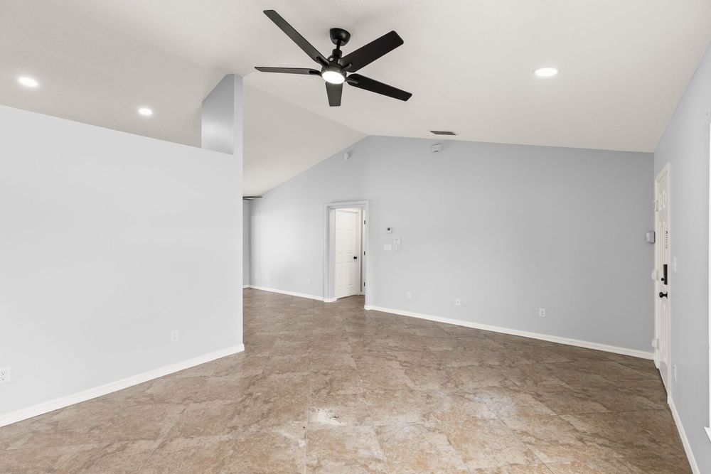 Spacious empty room with neutral walls, modern ceiling fan, and recessed lighting.