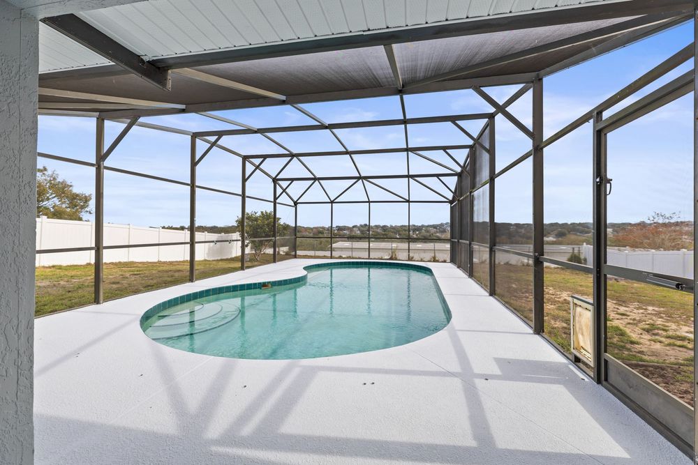 Screened pool enclosure with clear view of the backyard through mesh panels.