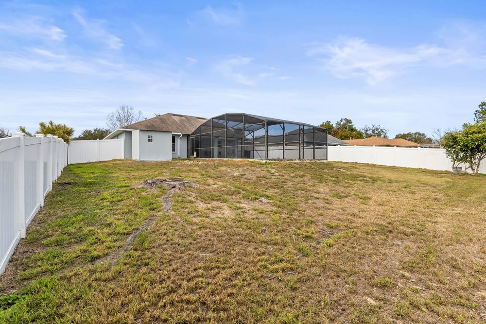 Aerial view of backyard with screened pool enclosure and white vinyl fencing.