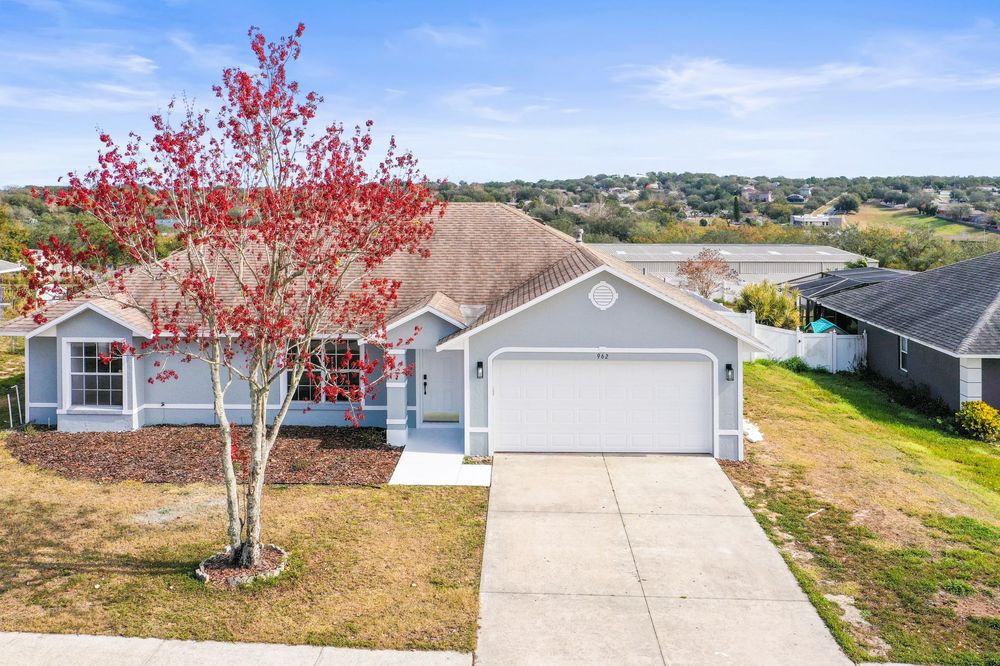 Modern single story home with gray siding and a pink flowering tree in the front yard.