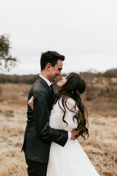 Wedding couple sharing intimate moment in winter field landscape.