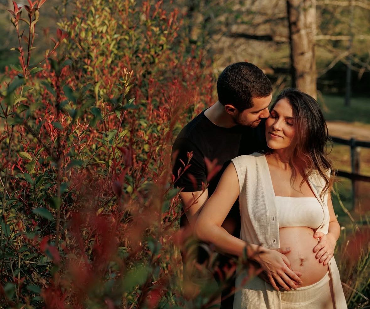 Romantic embrace among red autumn foliage during outdoor portrait session.