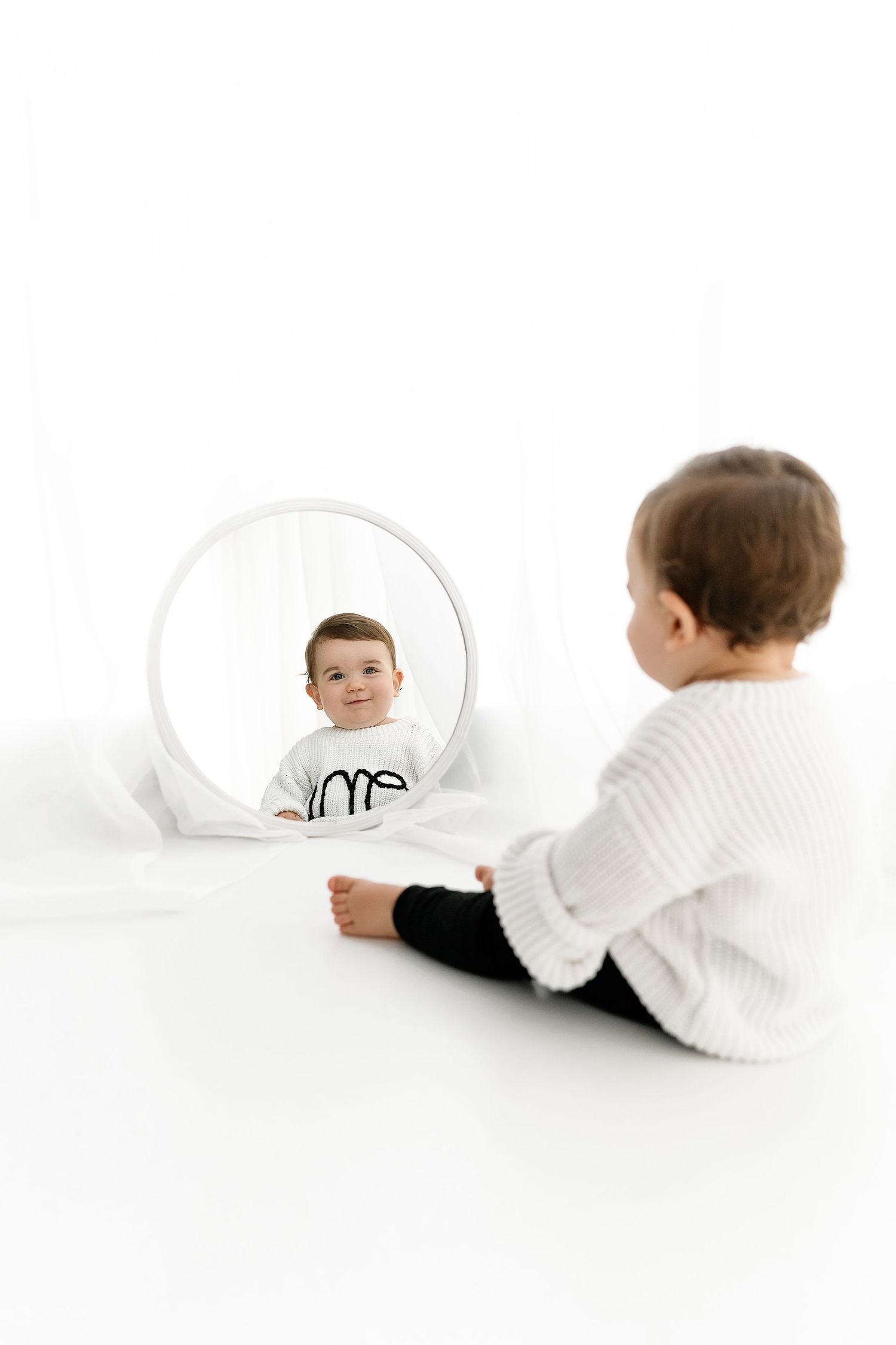 A creative photo collage showing moving reflections of a small child in white sweater across multiple circular mirrors.