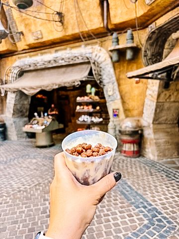 Themed snack served in a paper cone against a rustic theme park backdrop.