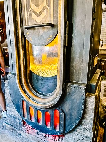 Vintage-style popcorn machine with yellow kernels visible through glass window.