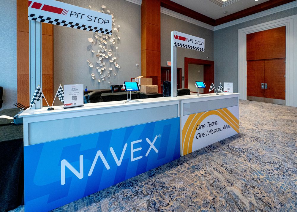 Modern corporate reception desk with NAVEX branding and racing-themed decorative elements.
