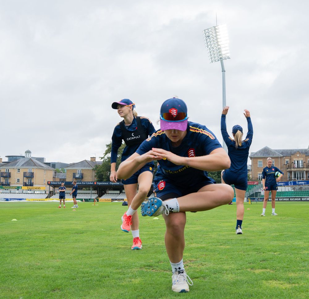 Athletes stretch and warm up on a sports field underneath stadium floodlights during a training session.